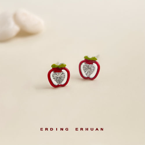 Mini red apple studs on pale surface with pebbles