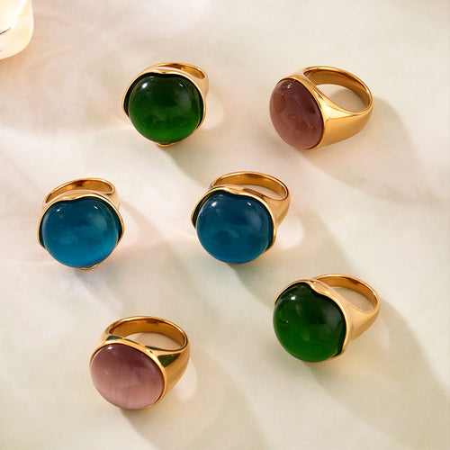 Six gold cat-eye rings in green blue gray on white cloth