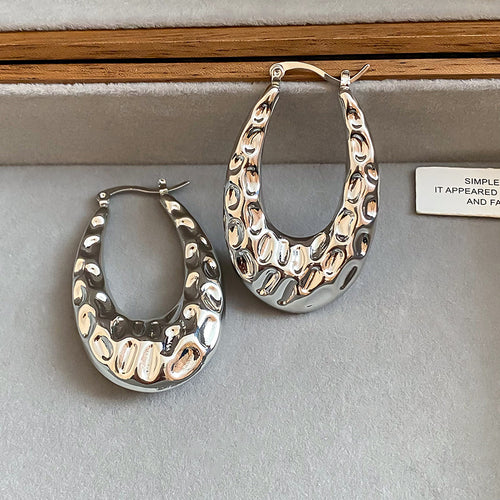 Chunky open oval hoops with an irregular hammered surface displayed from the front.