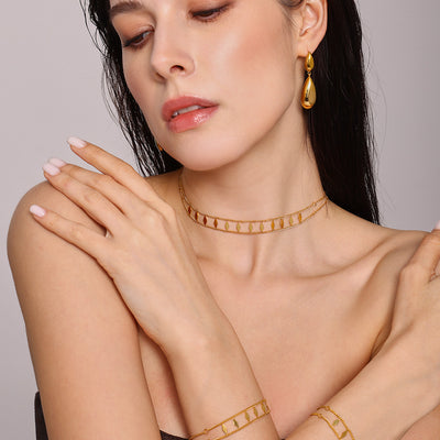 Model wearing gold rhombus charm choker necklace and bracelets