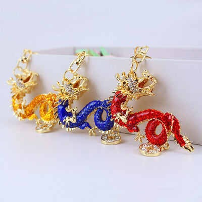 Red, blue, and amber-gold dragon charms are arranged together on a white surface.