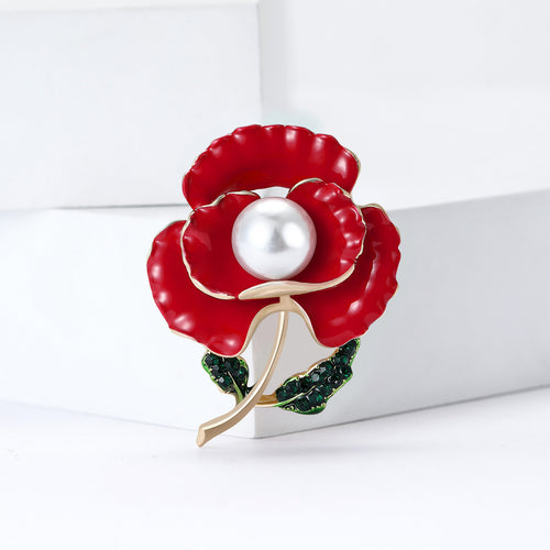 Red poppy brooch angled on white display blocks