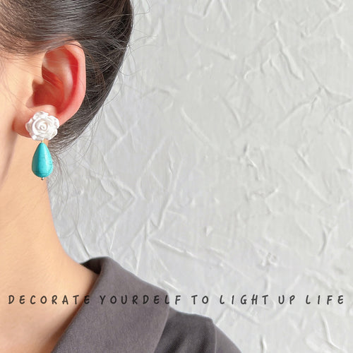 White-rose aqua-veined-teardrop studs shown worn on an ear.