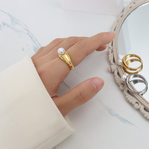 Gold dome side pearl ring worn on hand beside mirror with stacked rings