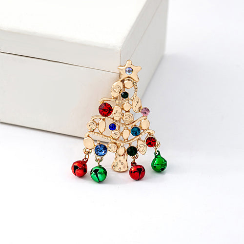 Gold Christmas tree brooch with crystal gems and bells on white surface