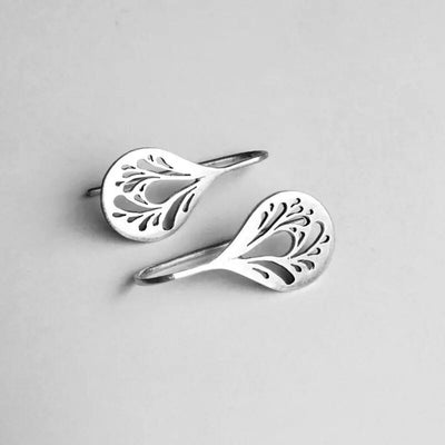Silver hollow leaf teardrop drop hook earrings on white surface