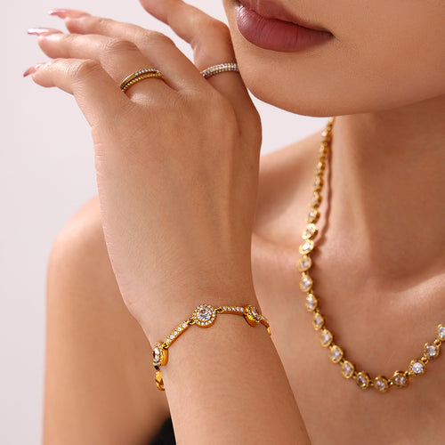 Gold halo zircon bracelet close-up with matching necklace in background