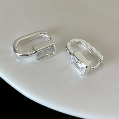 Silver rectangular clear stone U-shaped huggie pair on white plate
