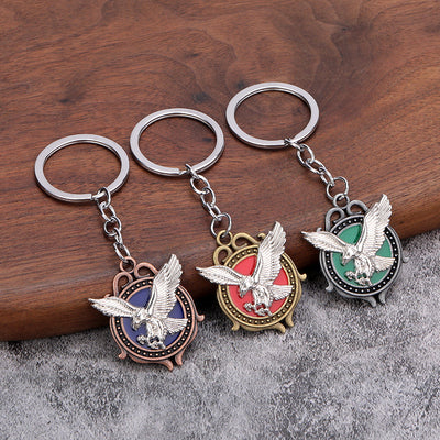 Three eagle keychains with blue, red, and green round medallions on a wooden surface.