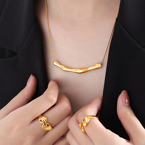 Gold wavy bar necklace worn with black blazer