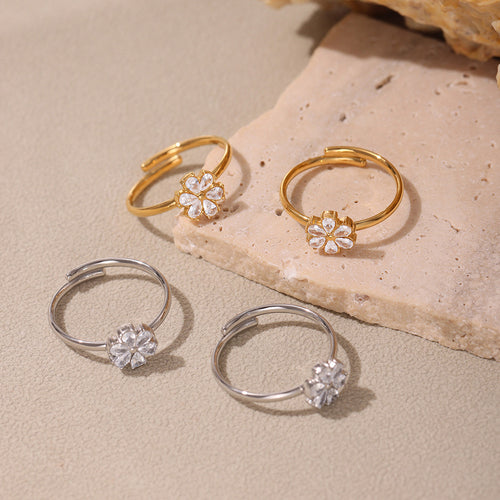 Gold and steel open flower zircon rings on stone surface