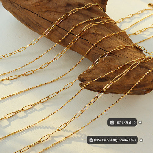 Gold paperclip and ball chains flat lay with plating and length labels