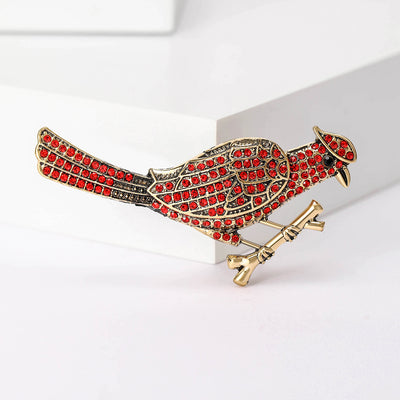Front view of the red bird brooch showing a red enamel bird with green details and clear crystal accents