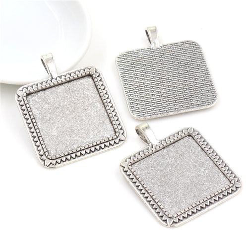 Grouped detail view of square pendant bezel trays with beaded borders and textured backs