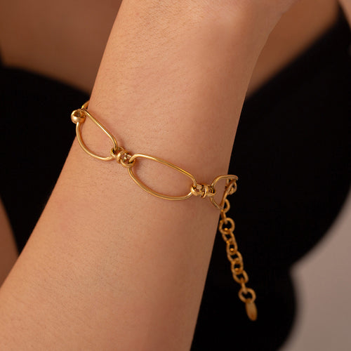 Gold oval link bracelet worn on wrist against black top