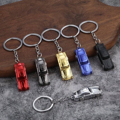 Six car-shaped metal keychains in red, gunmetal, gold, blue, matte black, and silver