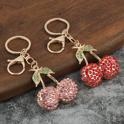 Red and pink rhinestone cherry keychains on wood