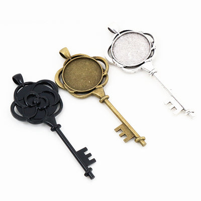 Key-shaped pendant with a flower back and round cabochon tray in a group view on a white background