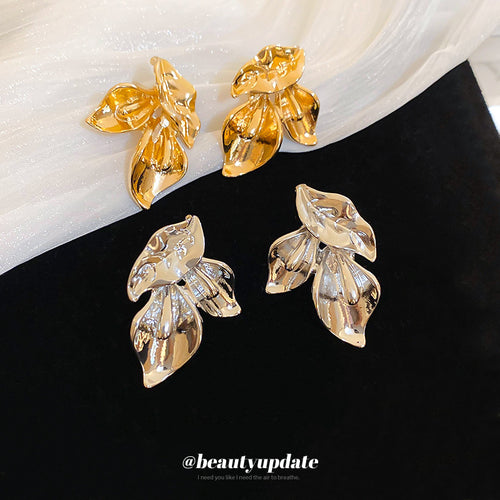 Product display of layered sculptural leaf stud earrings in two tones