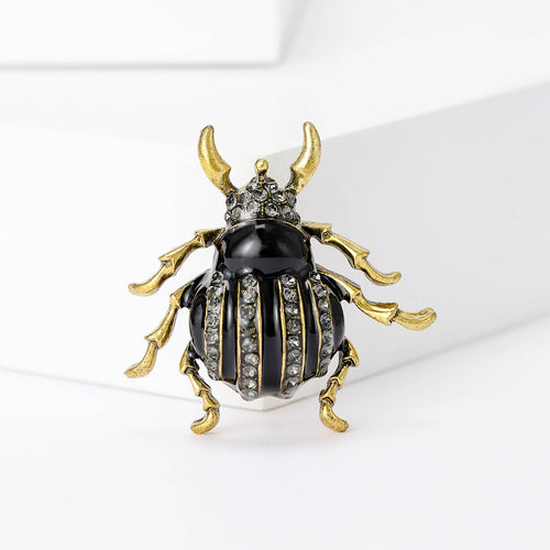 Black enamel rhinestone beetle brooch front on white blocks