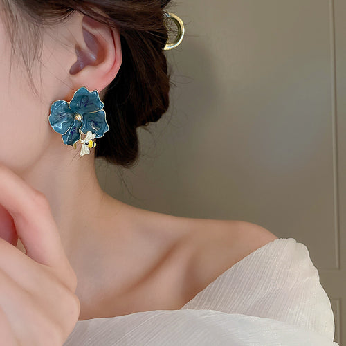 Styled close-up of blue floral statement earrings