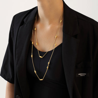 Gold oval bead station necklace layered over black tank