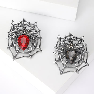 A sculpted web holding a dark metal spider with faceted abdomen shown on a white background.