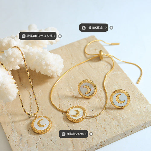 Flat lay of gold moon necklace, slider bracelet, and studs with size labels