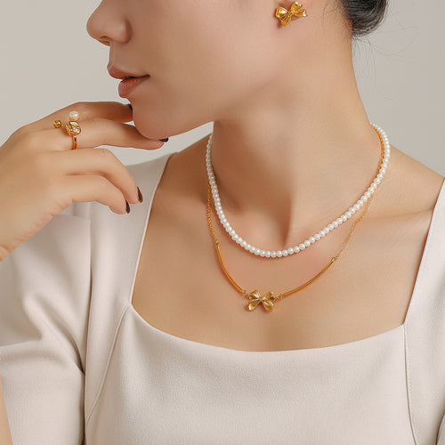 Layered pearl strand and gold bow bar necklace with bow studs