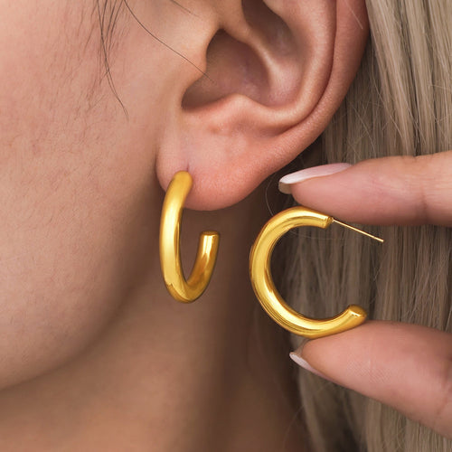 Model wearing gold C hoop with matching earring held near ear