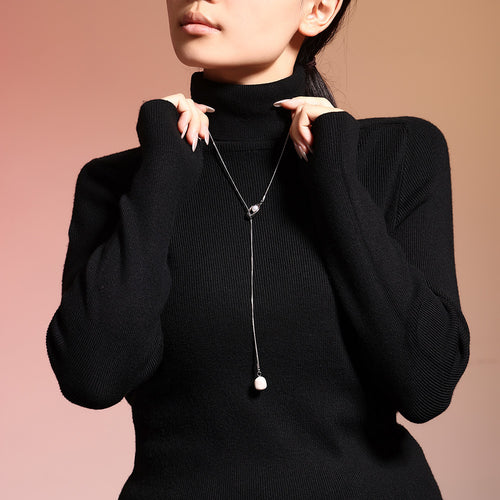 Silver steel lariat necklace with pearl drop on black turtleneck