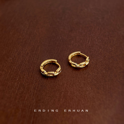 Mini gold chain link huggie hoops on dark wood