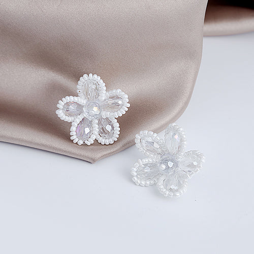 White crystal flower studs on satin fabric and white surface