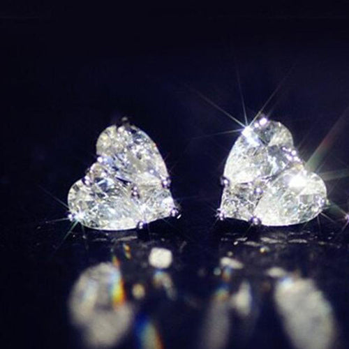 Clear heart stud earrings close-up with strong light flares