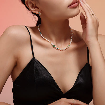 Model front view wearing pearl and green bead necklace on black top