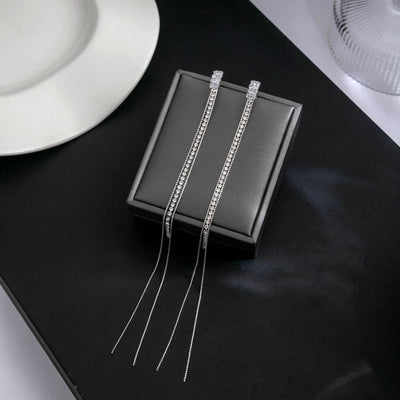 Silver long crystal tassel earrings draped over black display block