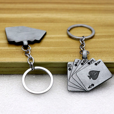 Front and reverse views of the fanned spade playing card keychain on a wooden surface.