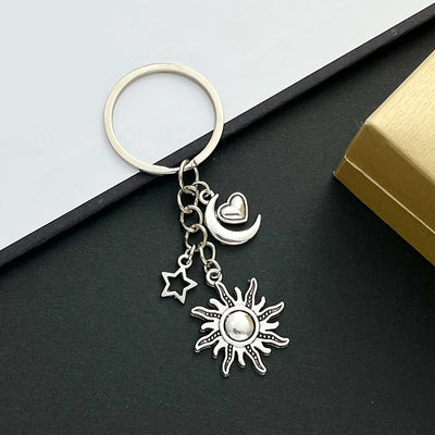 Front product photo of antique silver sun moon heart and star celestial charm keychain showing the pictured design arran