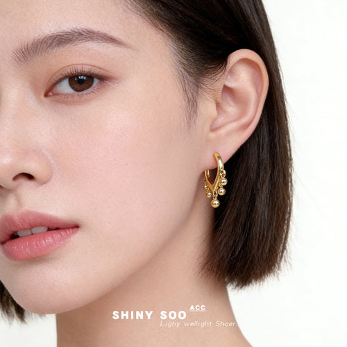 Gold heart hoop with dangling balls worn on model ear