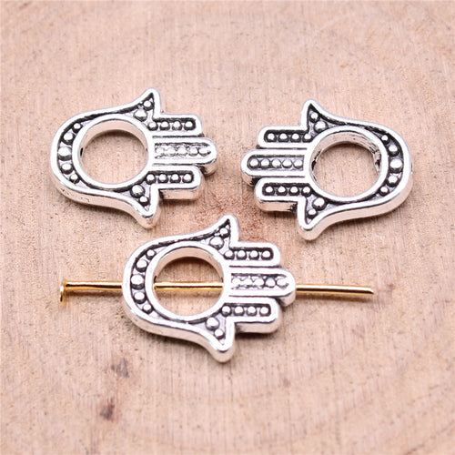 Open hamsa hand silhouette with dotted details and a central hole shown close up on a hand