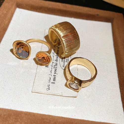 Three gold rings ribbed cuff clear stone dual amber on linen card