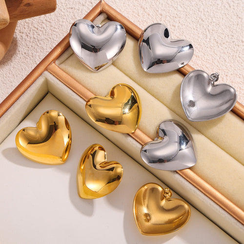 Gold and steel heart studs in cream jewelry tray showing backs and fronts