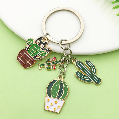 A multicolor cactus keychain with four linked charms arranged on a pale green surface.
