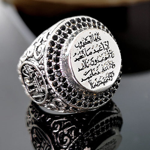 Antique silver engraved script signet ring angled on dark glass