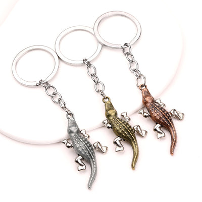 Three crocodile keychains displayed together in bronze, silver, and copper tones.