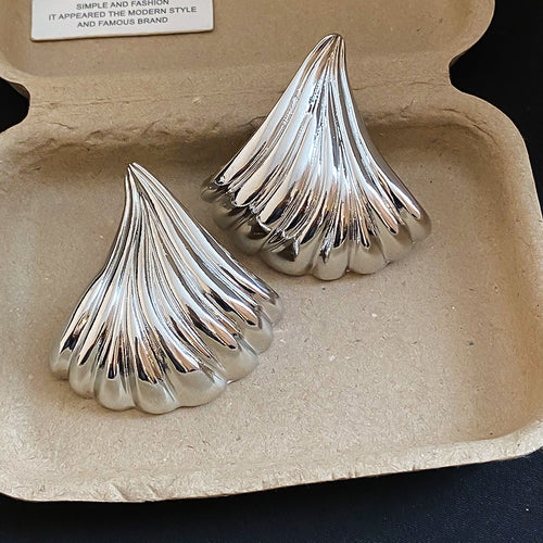 Oversized fluted fan shapes with a polished metallic finish displayed in a close product arrangement.