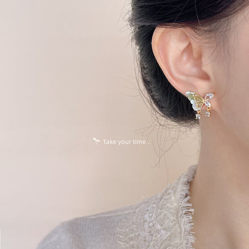 Gold-tone multicolor-butterfly clear-stone tassel studs shown worn on an ear.