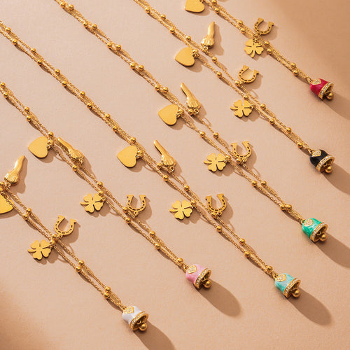 Overhead view multiple gold enamel bell charm necklaces on beige surface