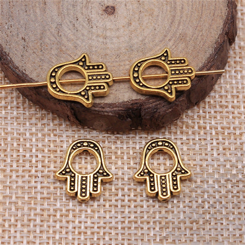 Open hamsa hand silhouette with dotted details and a central hole displayed on a natural wood setting