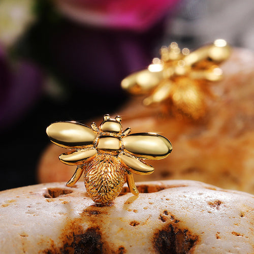 Close gold bee stud on porous stone with second bee soft in background